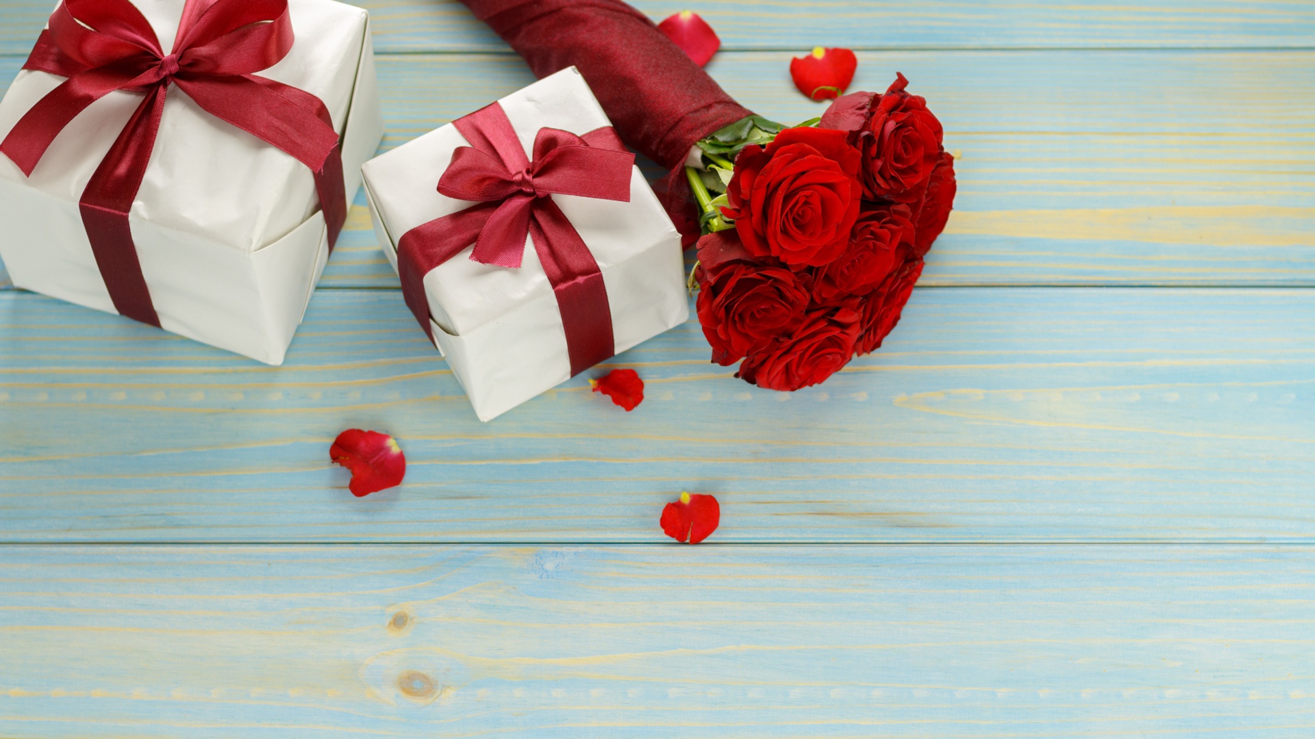 Букет красных роз с подарками на столе