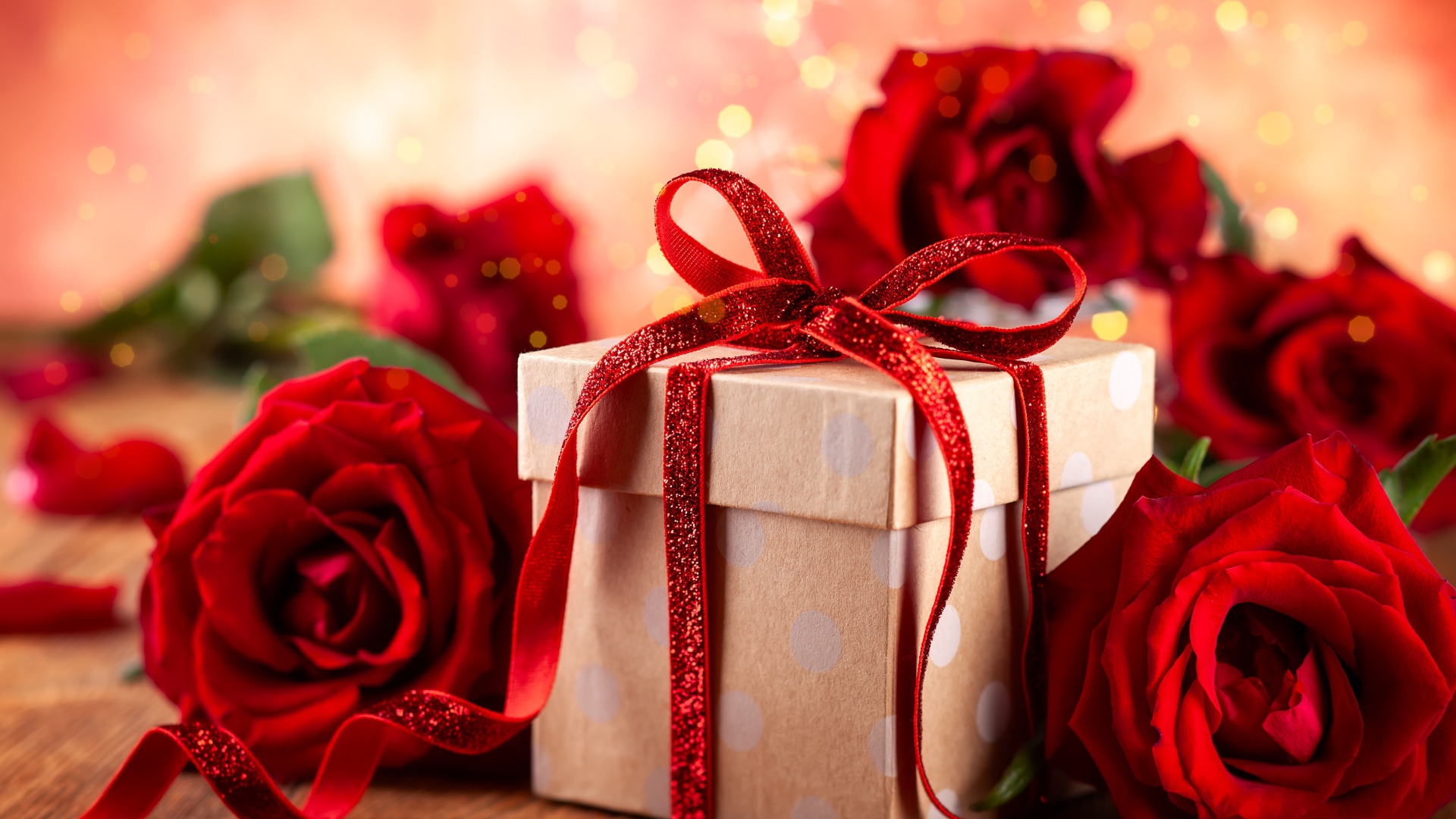 Подарок с красным бантом на столе с букетом роз