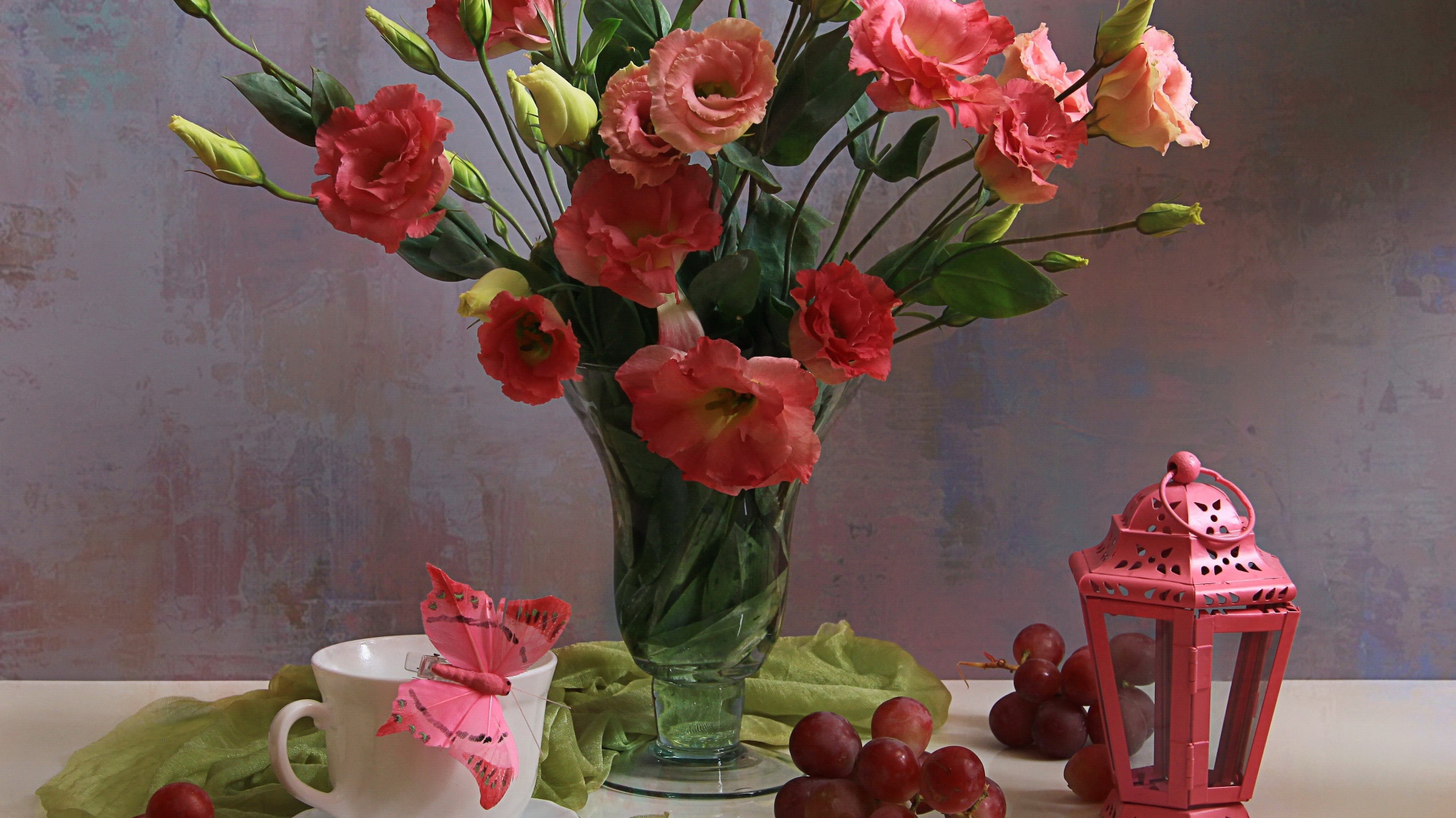 Букет розовых цветов эустомы на столе с виноградом