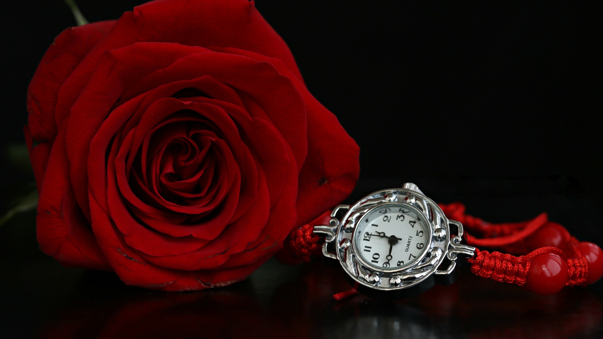 Красная роза с часами на черном фоне
