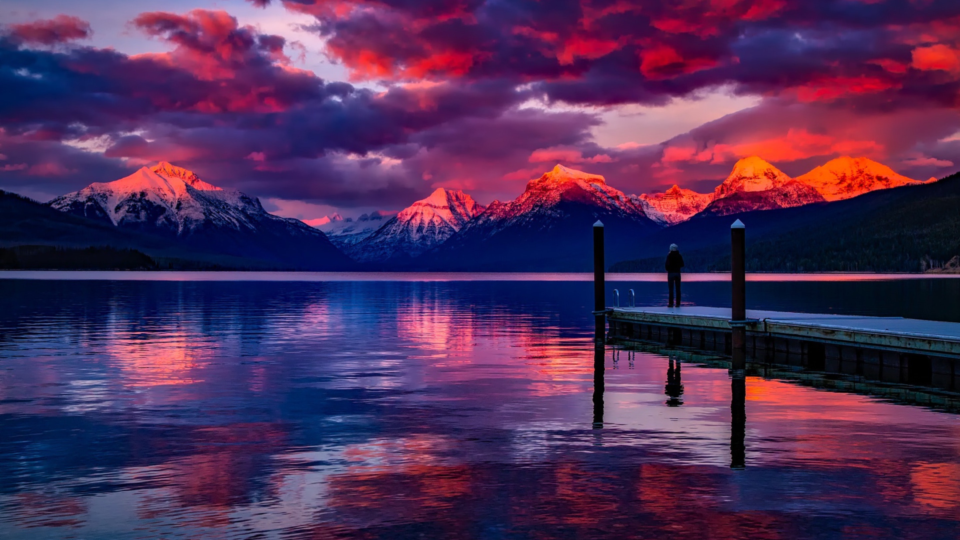 Красивый закат в небе над вершинами заснеженных гор у озера