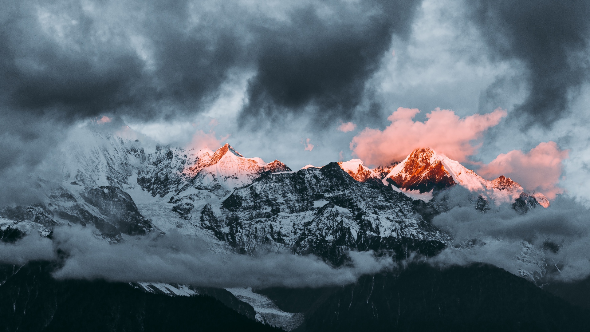 Солнце на рассвете освещает вершины заснеженных гор 