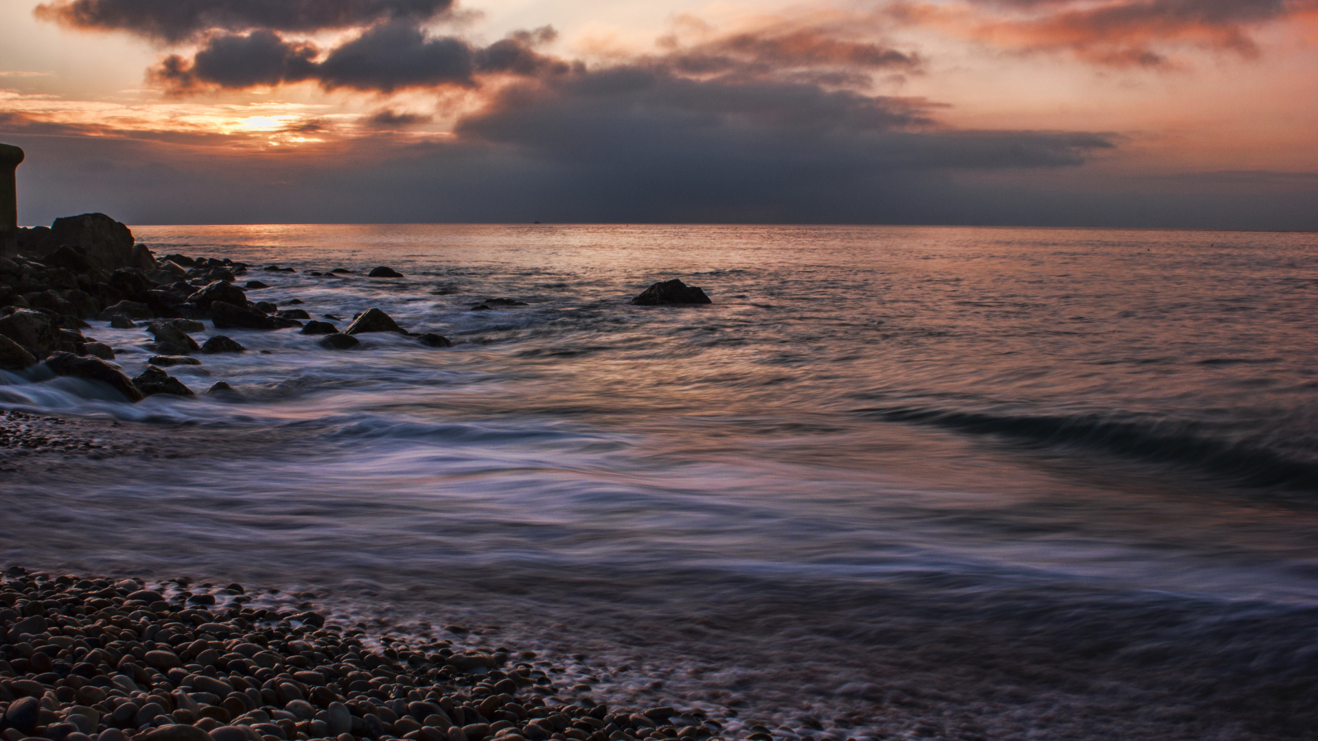 Мелкие камни на берегу моря на закате