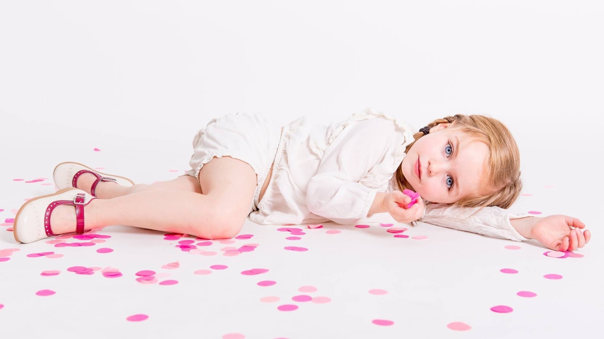 Маленькая голубоглазая девочка лежит на полу