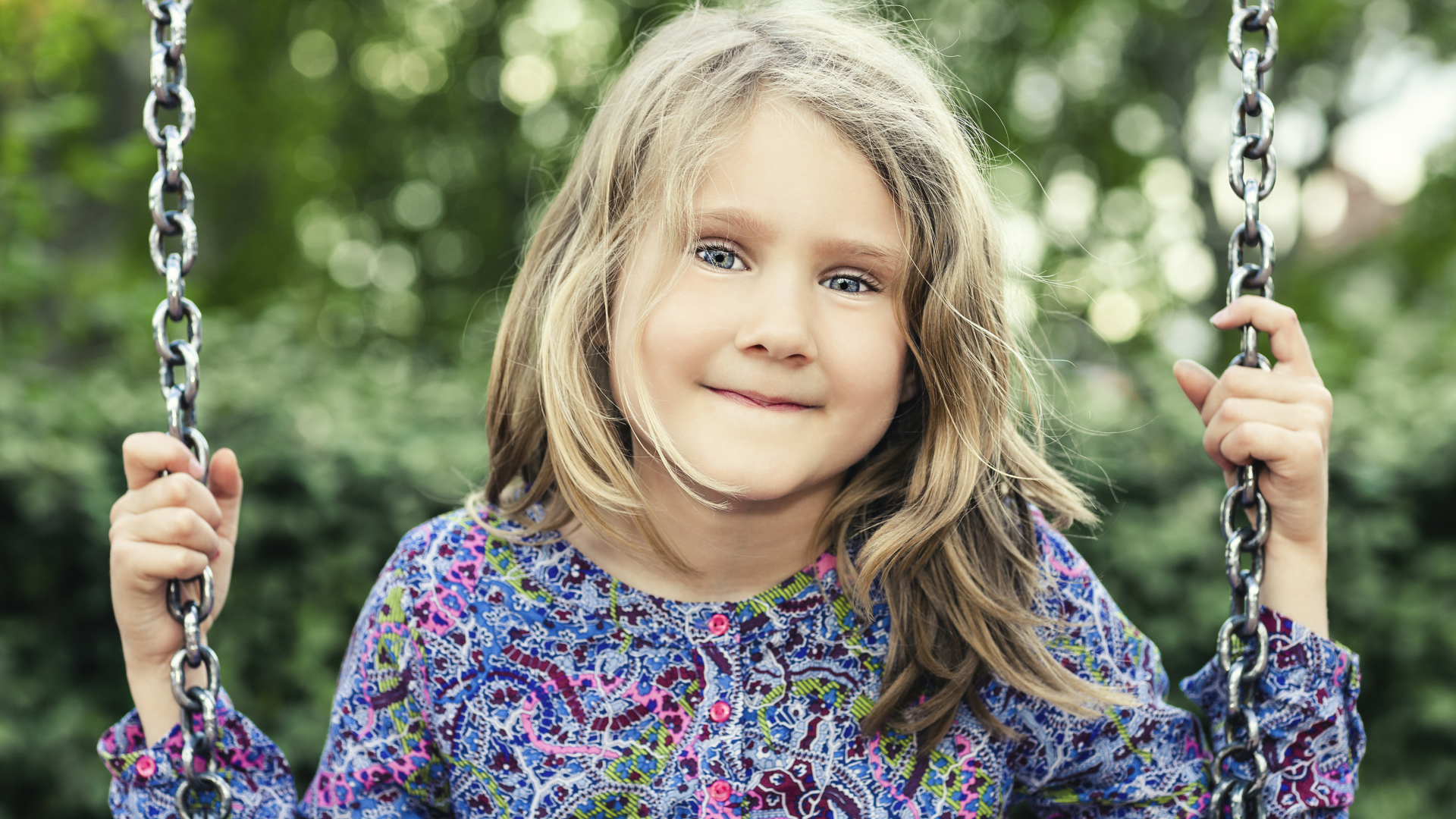Маленькая милая голубоглазая девочка на качели