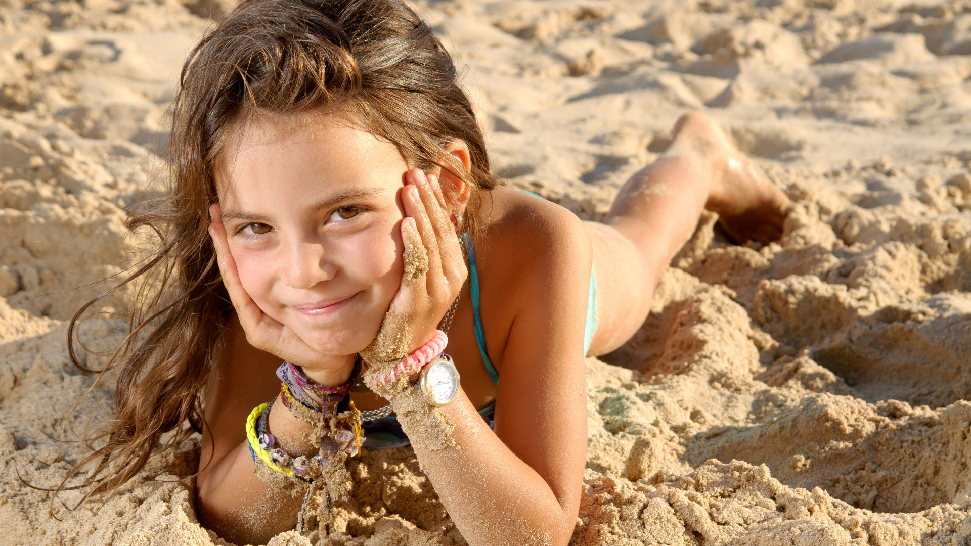 Маленькая девочка лежит на песке на пляже