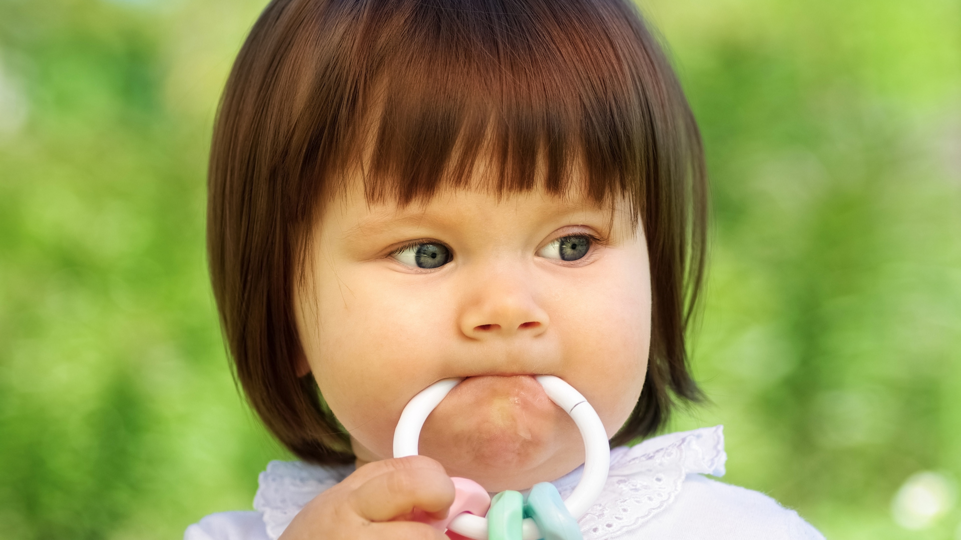Маленькая девочка с погремушкой во рту