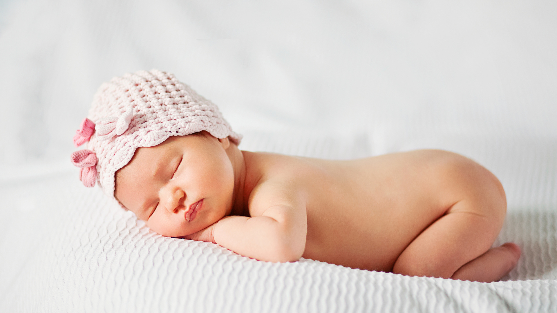 Спящий грудной ребенок девочка на белом покрывале