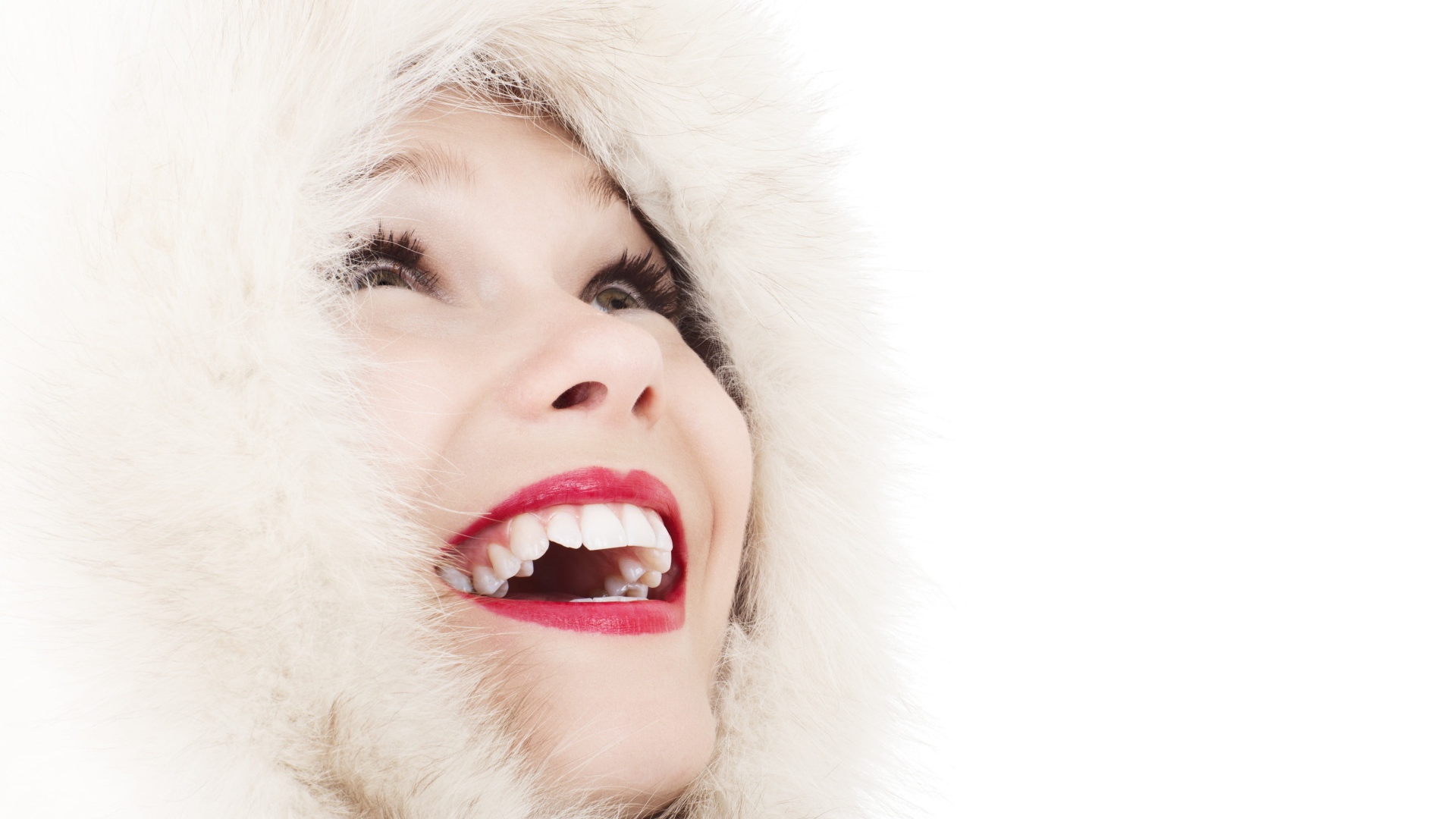 Улыбающаяся девушка в меховом капюшоне на белом фоне