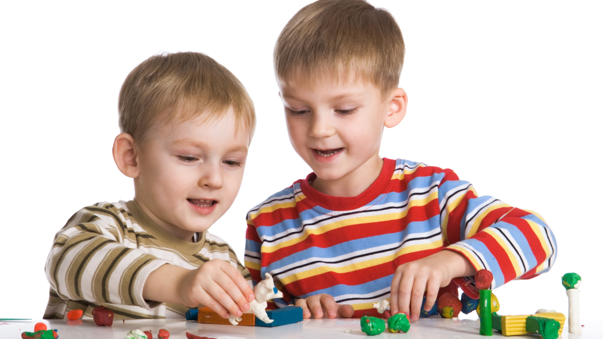 Два мальчика играют в игрушки на белом фоне