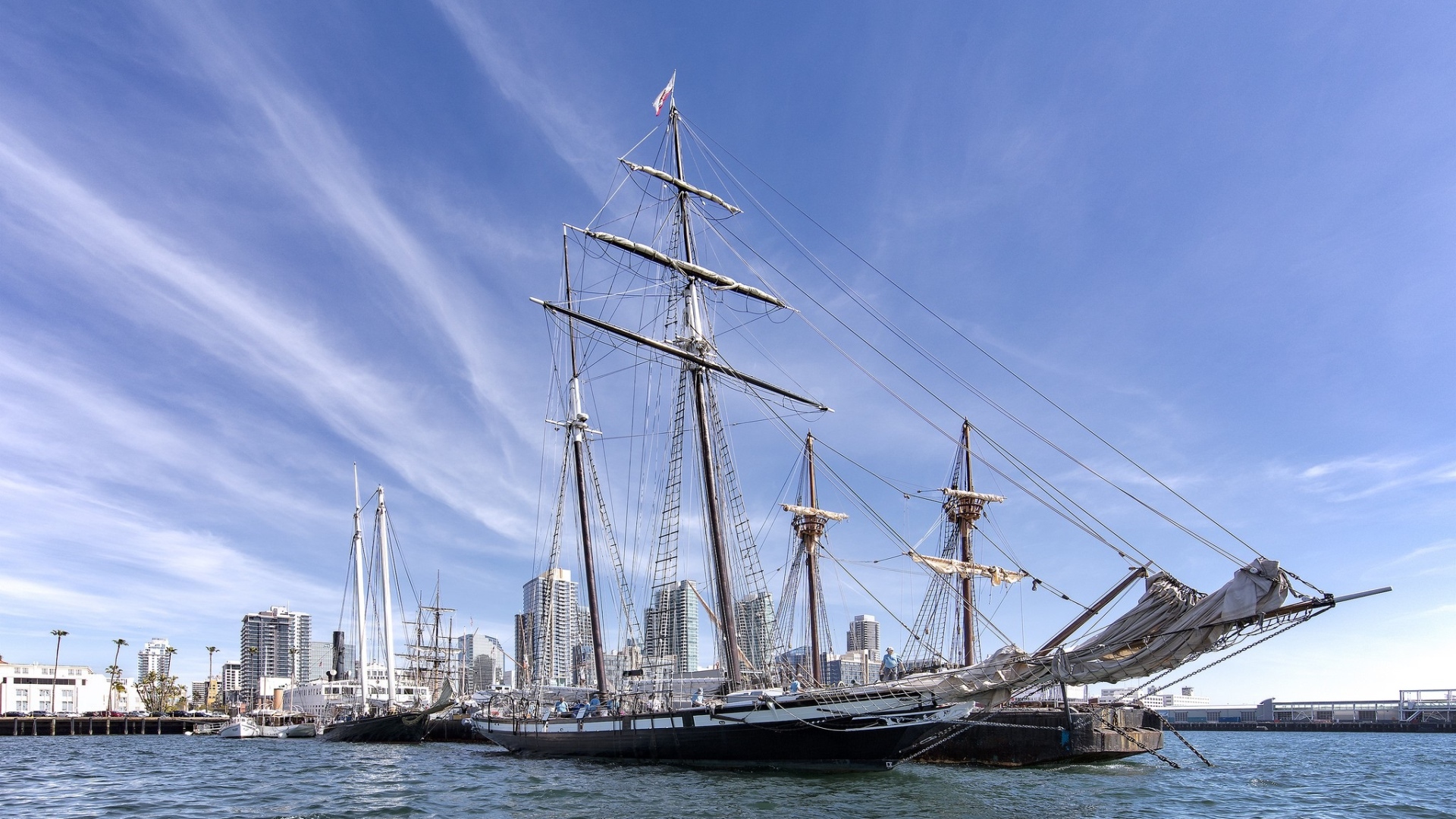 Большая парусная лодка на фоне голубого неба в порту у города