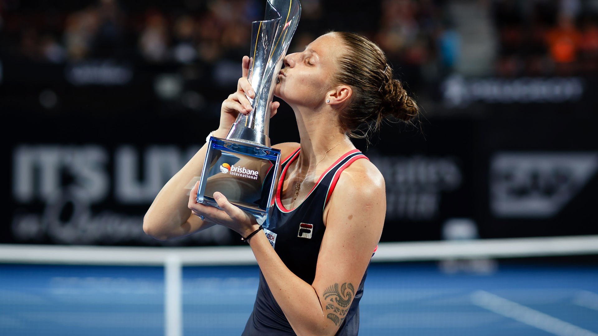 Чешская теннисистка Каролина Плишкова целует кубок на корте