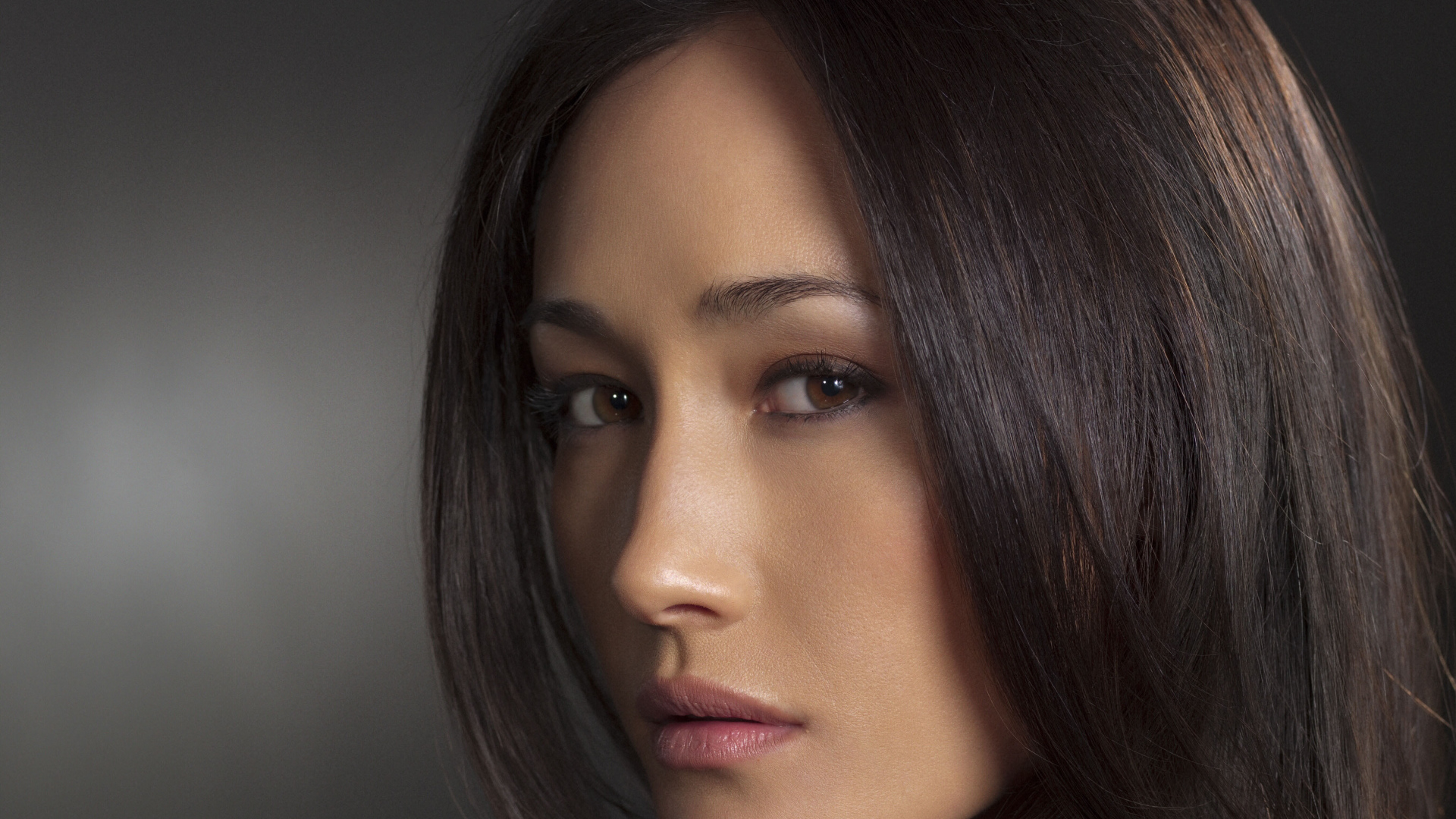 Актриса Мэгги Кью лицо крупным планом на сером фоне