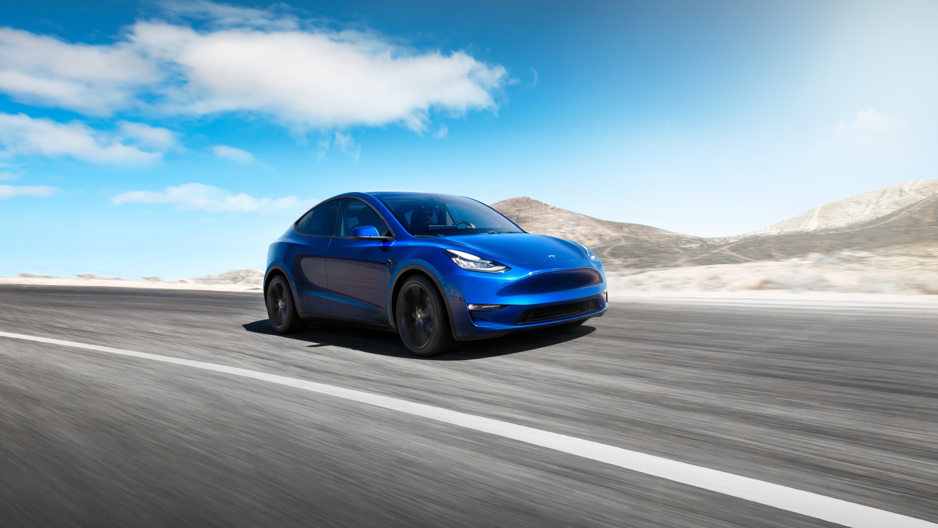 Синий автомобиль Tesla Model Y 2020 года на фоне голубого неба