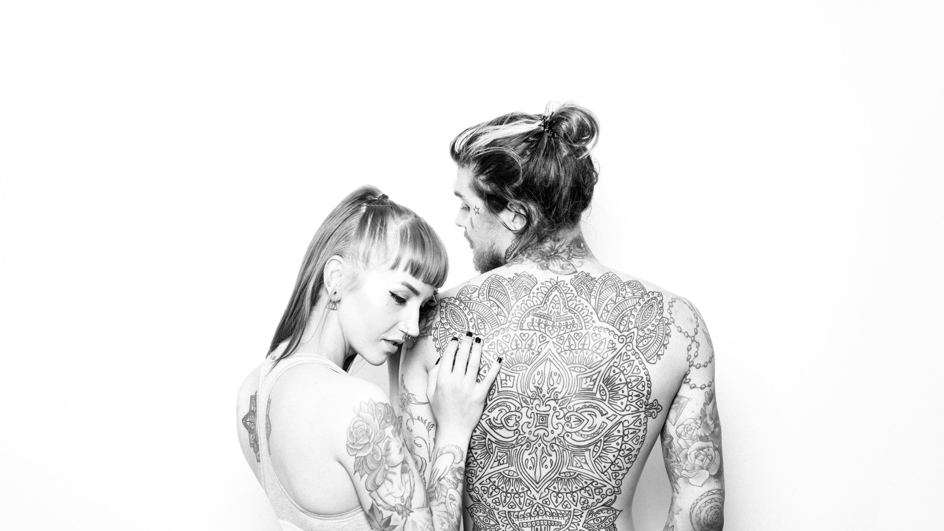 Мужчина и девушка с татуировками на теле на белом фоне