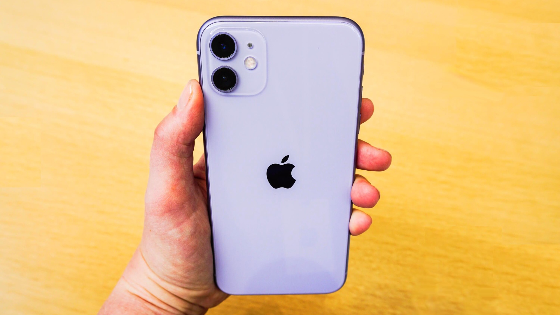 Новый Iphone 11 Pro Max в руке на желтом фоне