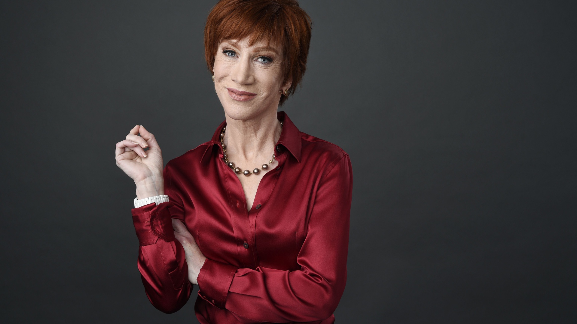 Рыжеволосая актриса Кэти Гриффин в красной рубашке на сером фоне