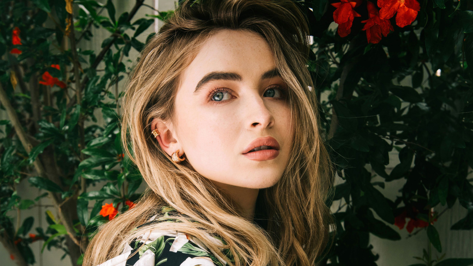 Молодая красивая актриса Сабрина Карпентер у красных цветов