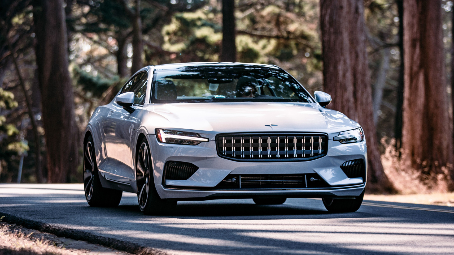 Белый автомобиль Polestar 1 2021 года едет по дороге