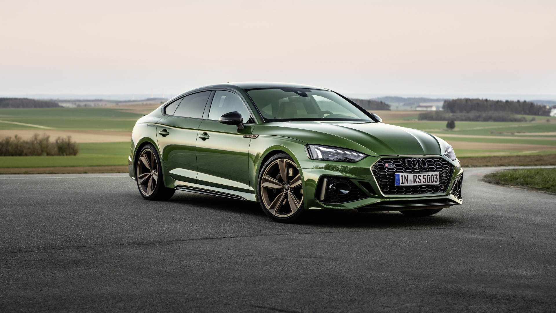 Зеленый автомобиль Audi RS 5 Sportback 2020 года на фоне поля