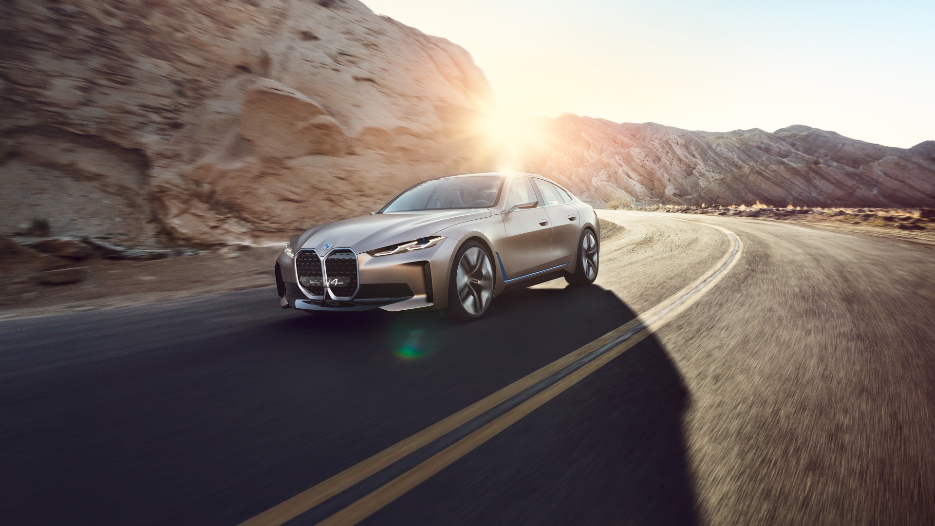 Автомобиль BMW Concept I4 2020 года у гор в лучах солнца