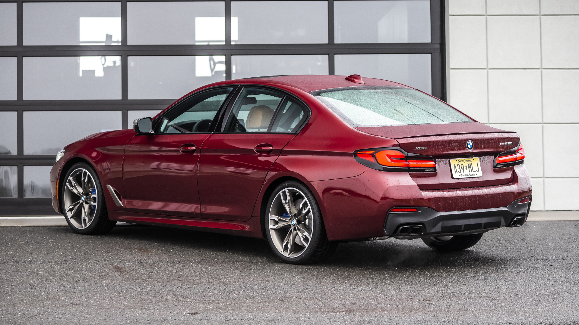 Красный автомобиль BMW M550i XDrive, 2021 года вид сзади