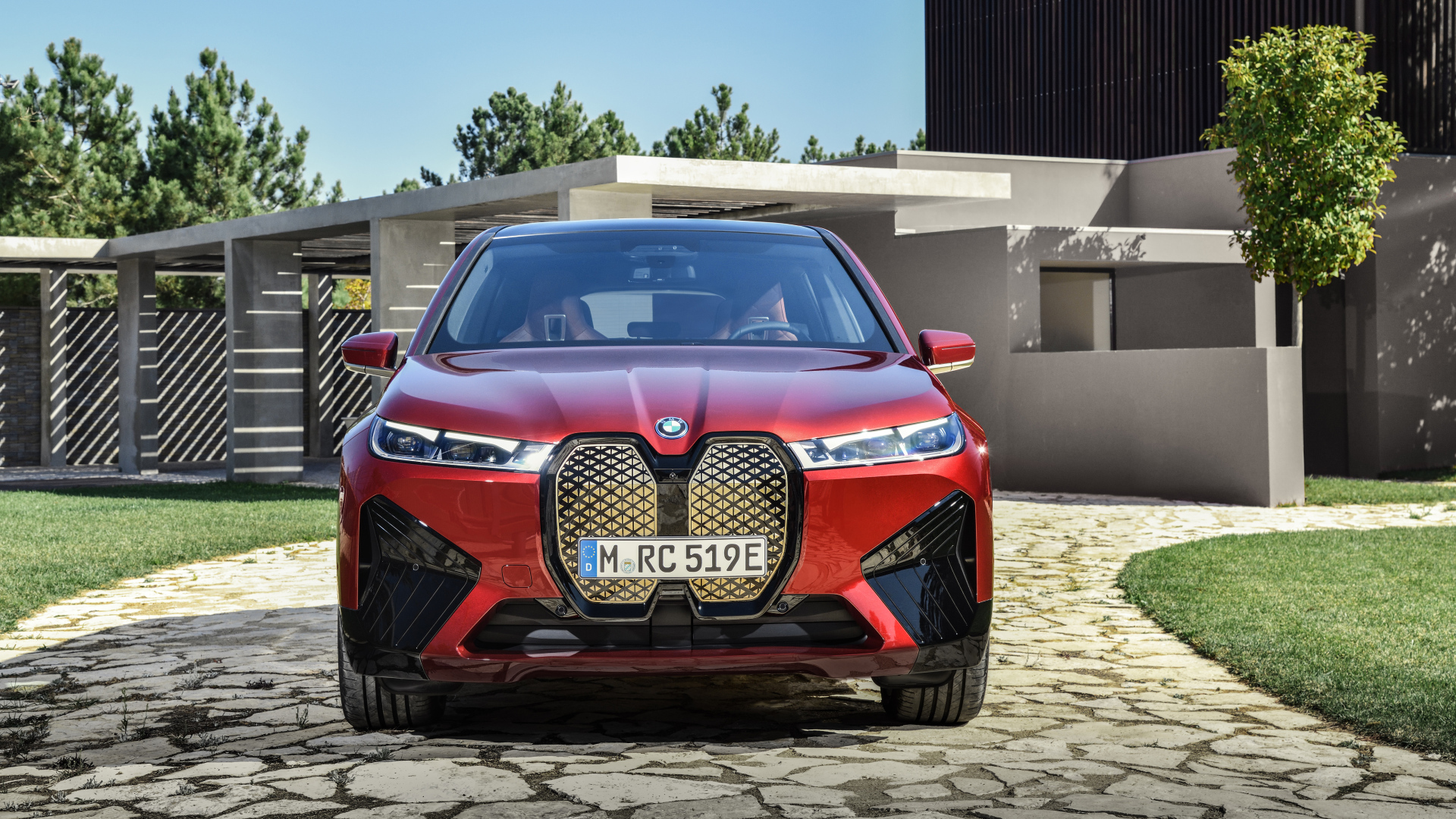 Красный автомобиль BMW IX 2021 года у дома