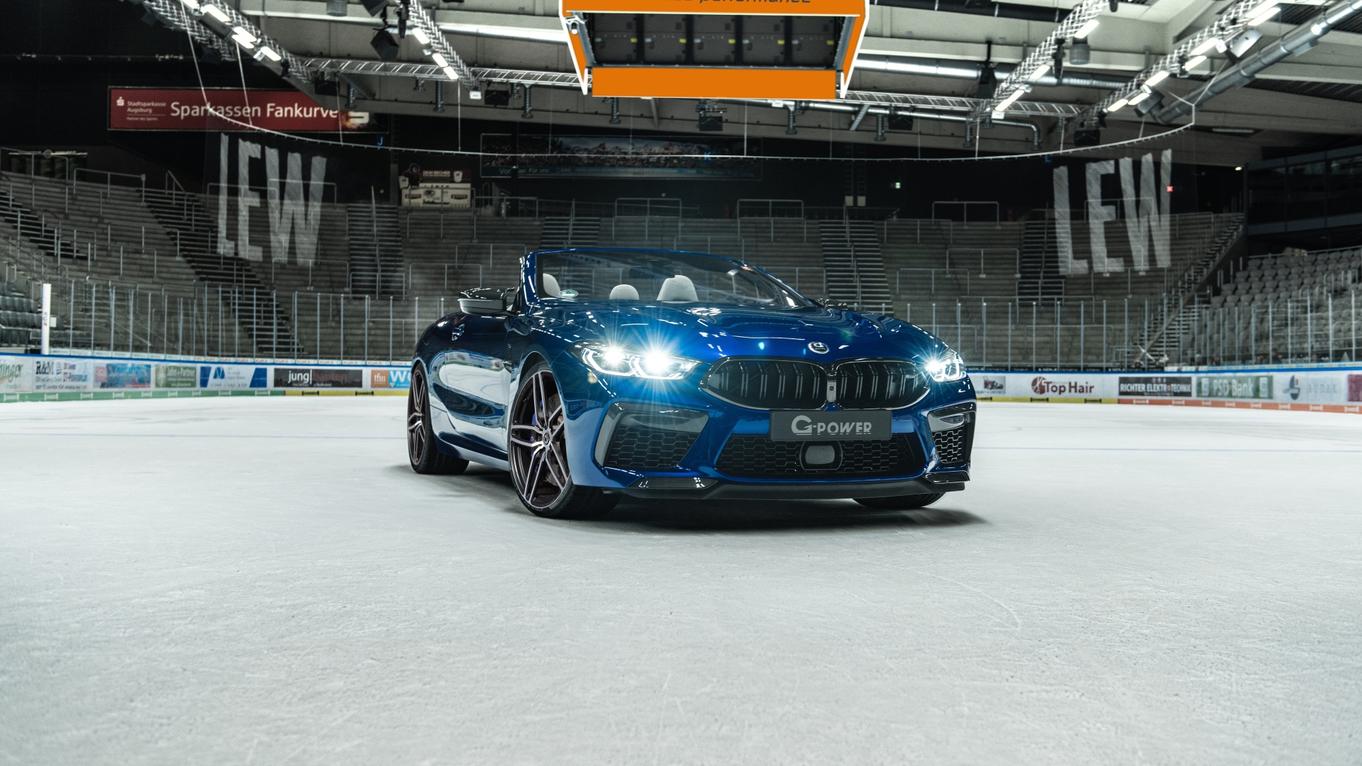 Кабриолет BMW M8,  2020 года с включенными фарами на стадионе 