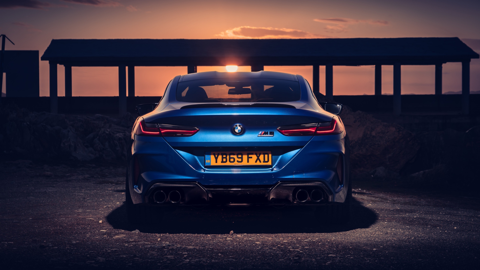 Синий автомобиль BMW M8, 2019 года на фоне заката 