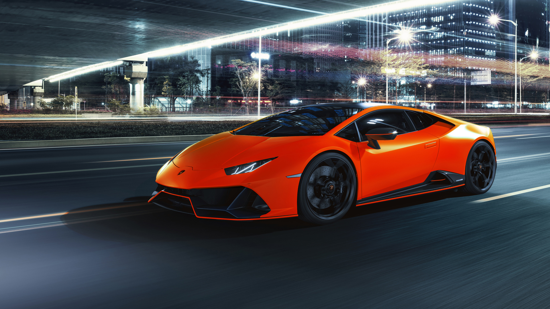 Оранжевый автомобиль Lamborghini Huracán EVO 2021 года на фоне города