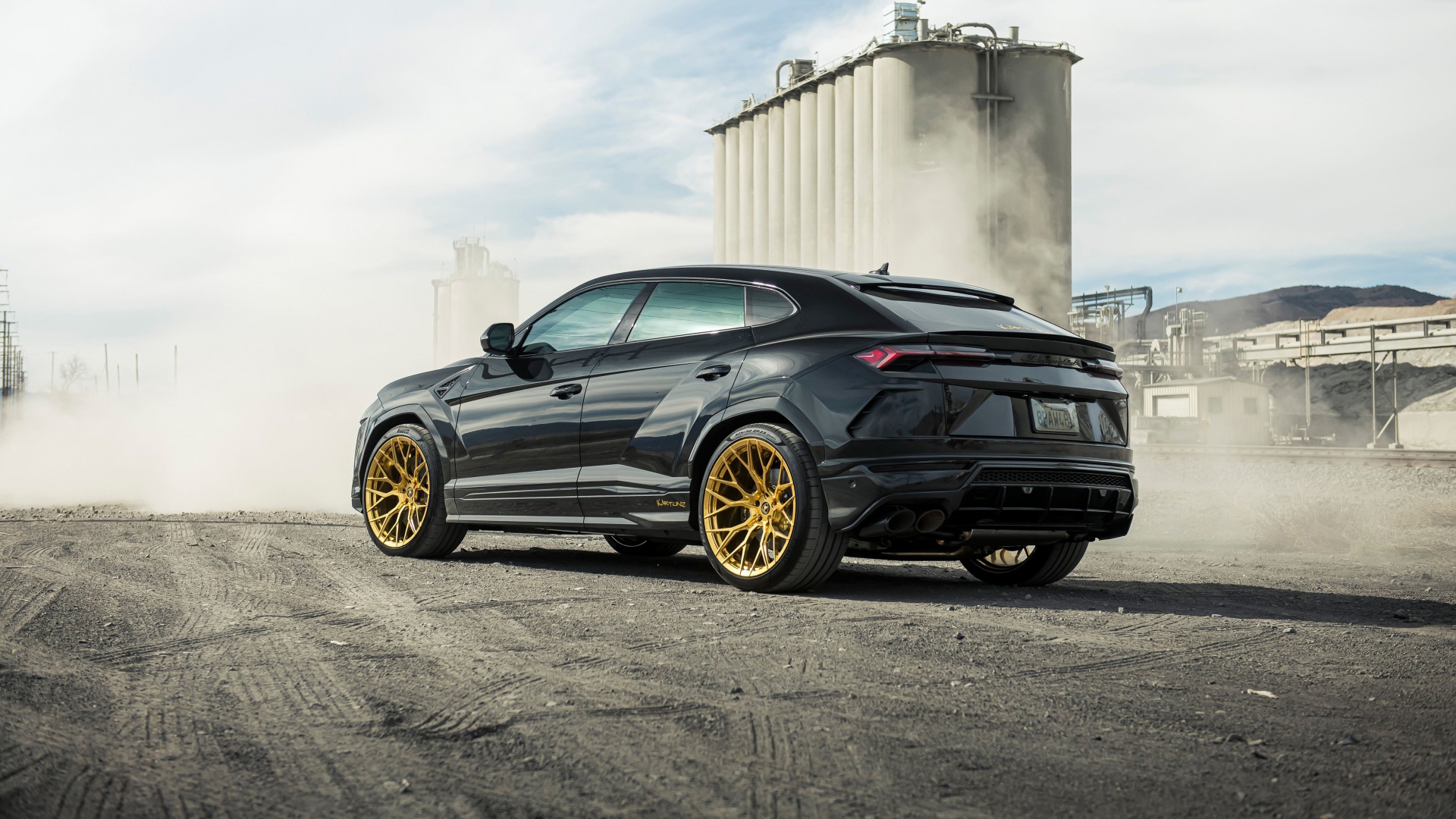 Черный внедорожник  Lamborghini Urus 2020 года на фоне завода вид сзади