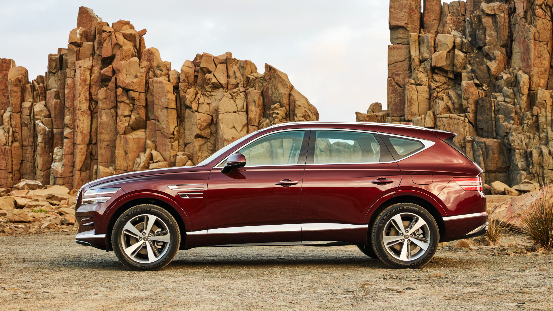 Бордовый автомобиль Genesis GV80 2.5T 2020 года на фоне гор