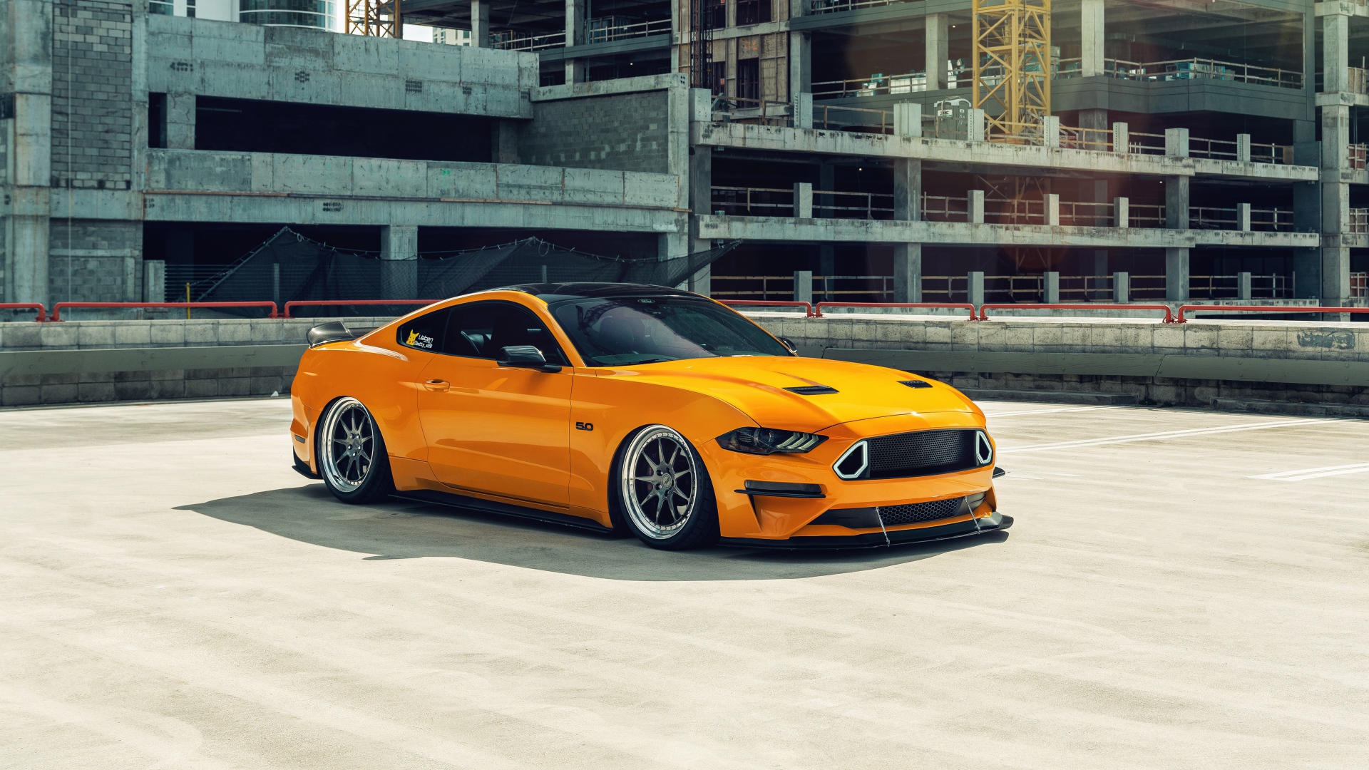 Оранжевый автомобиль Mustang у заброшенного здания 