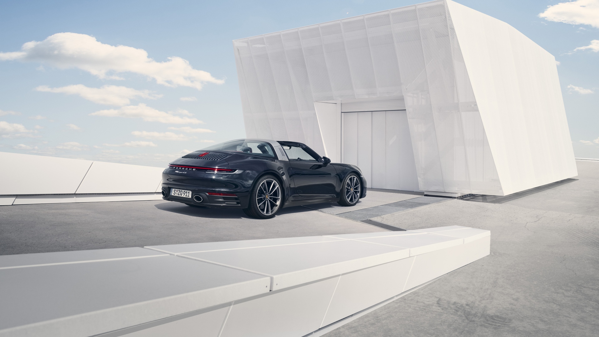 Черный автомобиль Porsche 911 Targa 4S 2020 года у гаража 