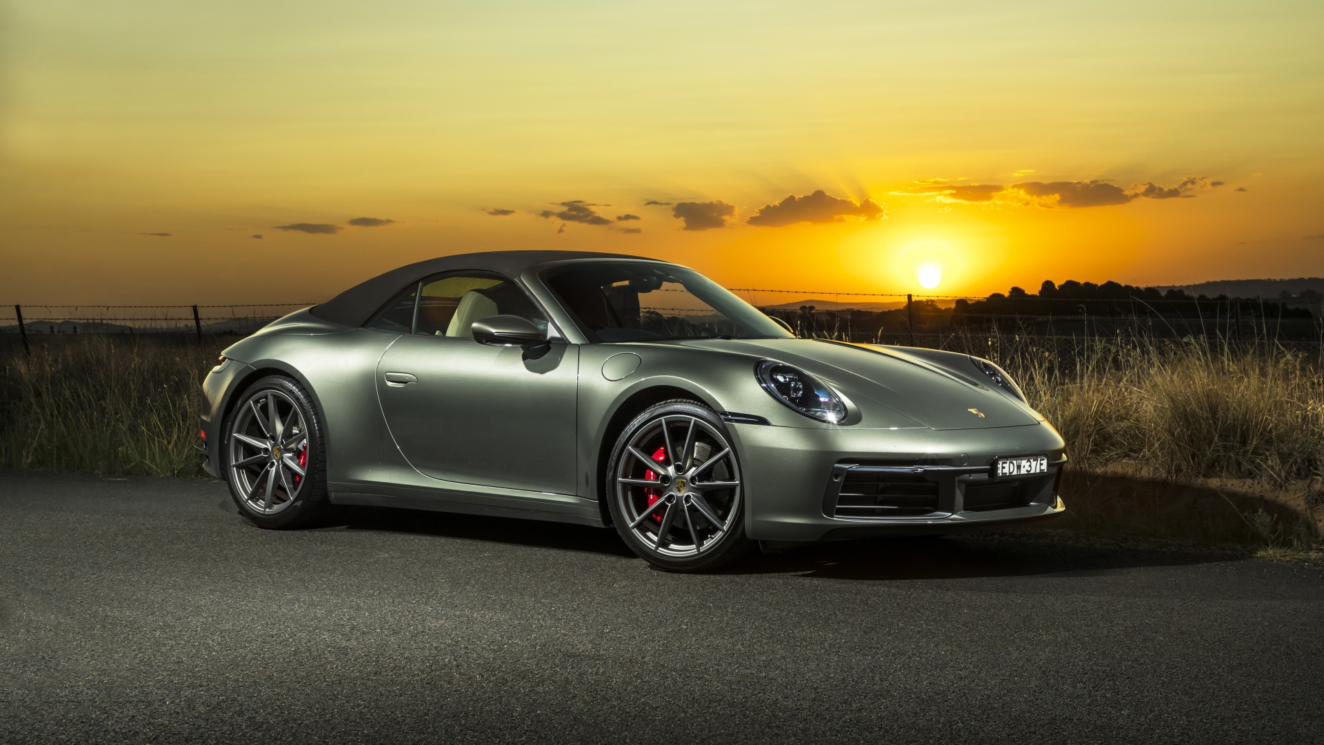 Серебристый Porsche 911 Carrera S Cabriolet 2020 года на закате 