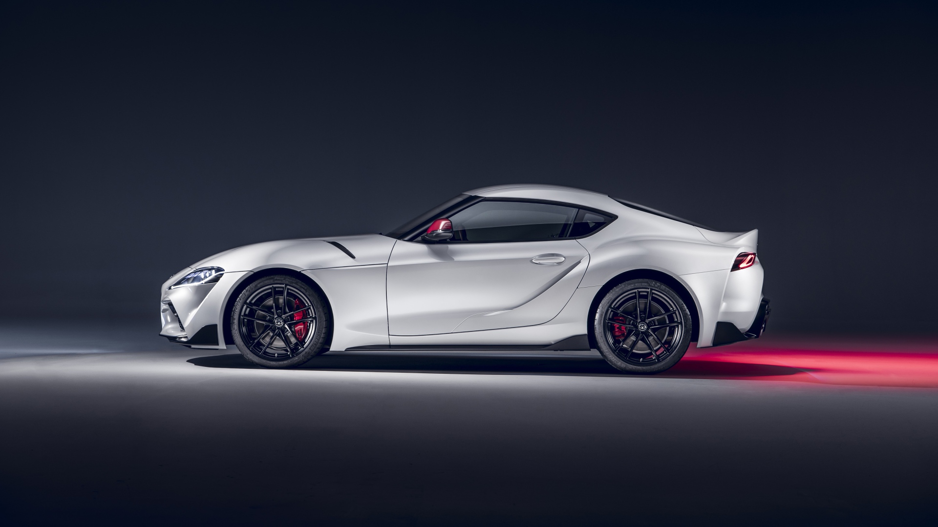 Серый автомобиль Toyota GR Supra 2L 2020 года вид сбоку на сером фоне
