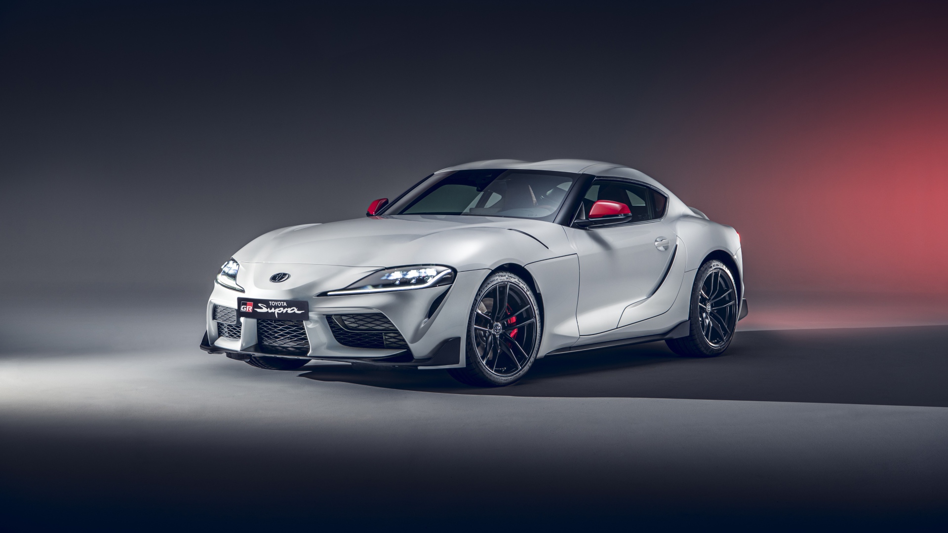 Серебристый автомобиль Toyota GR Supra 2L 2020 года на сером фоне