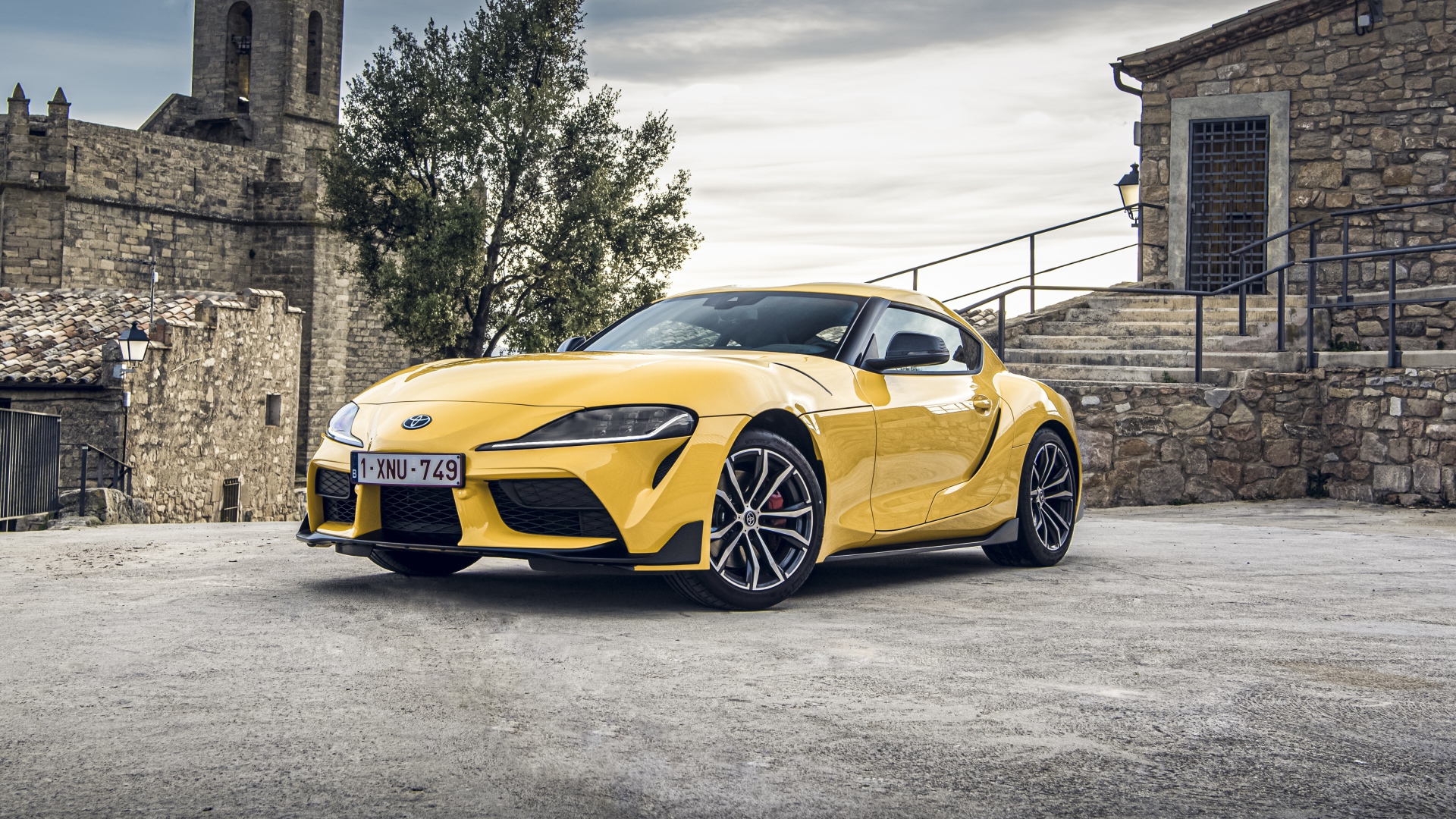 Желтый автомобиль Toyota GR Supra 2, 2020 года у старого здания 