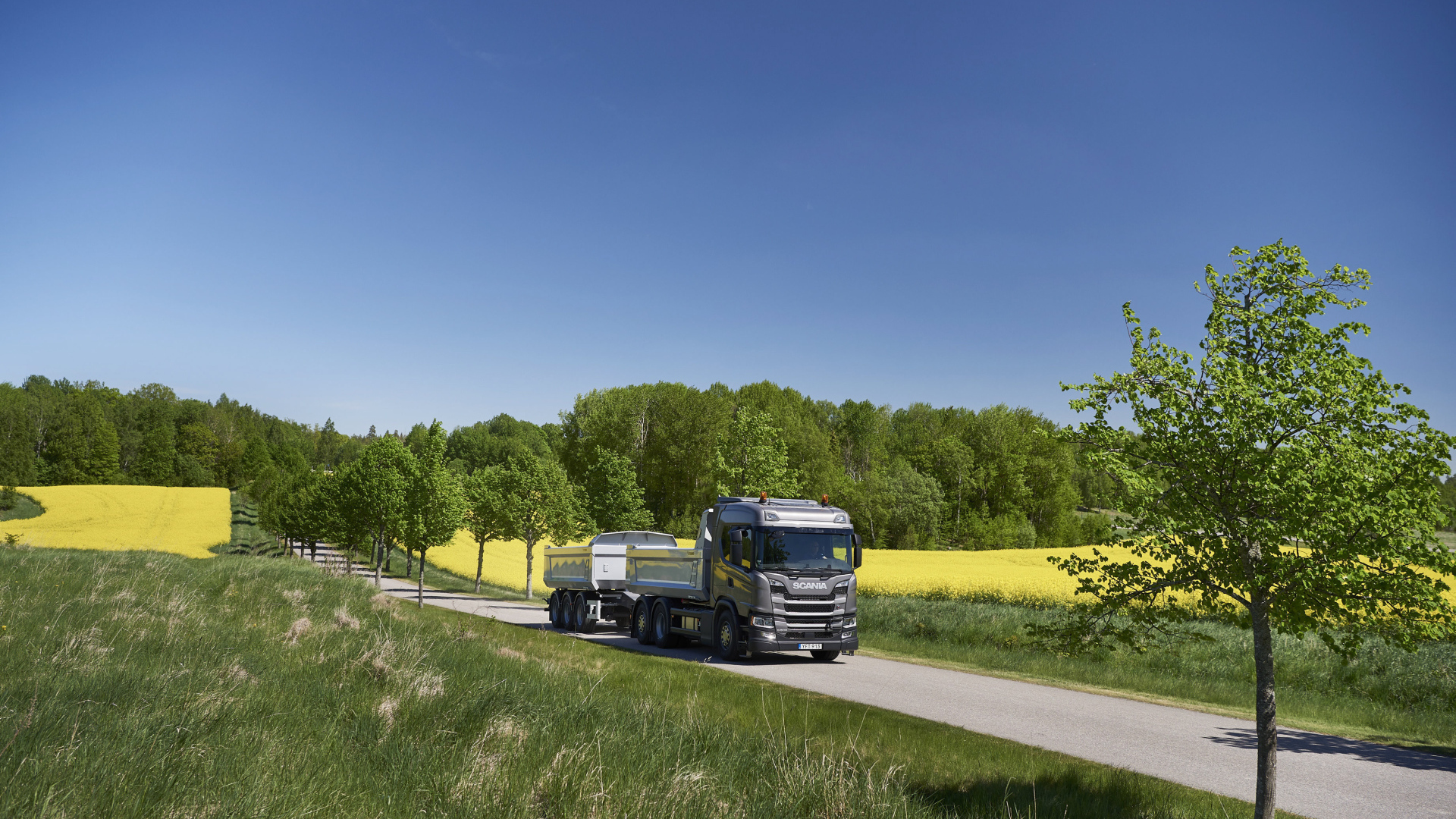 Грузовик Scania Trucks на трассе у поля