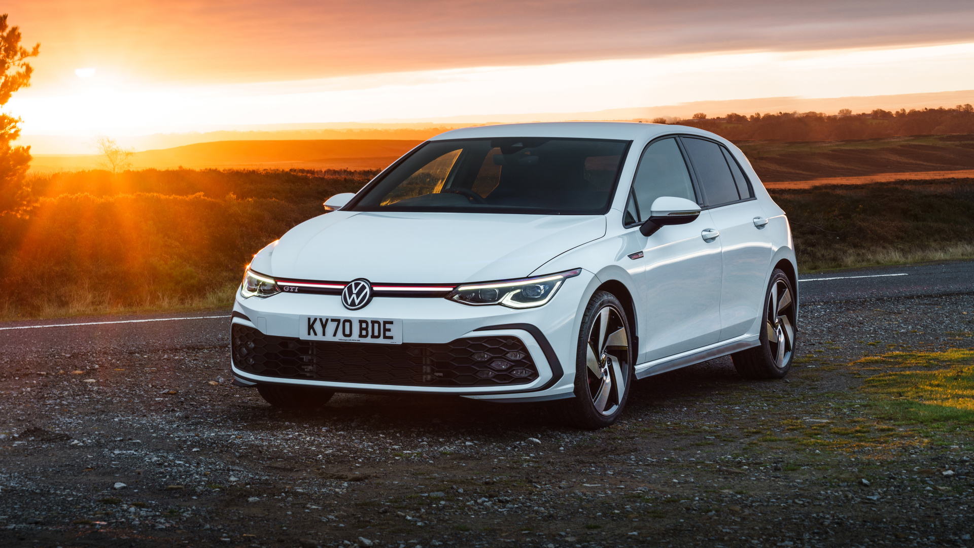 Белый автомобиль Volkswagen Golf GTI 2020 года на закате солнца