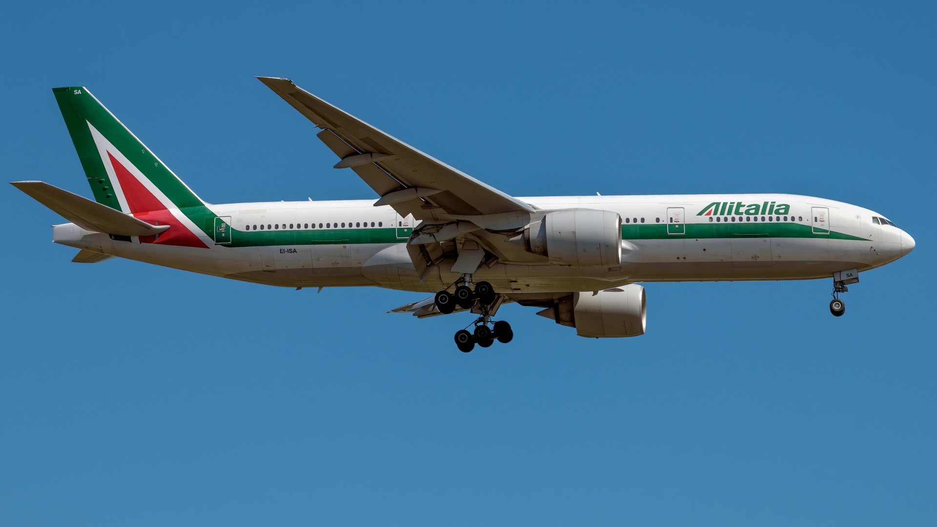 Пассажирский  самолет авиакомпании Alitalia в голубом небе 