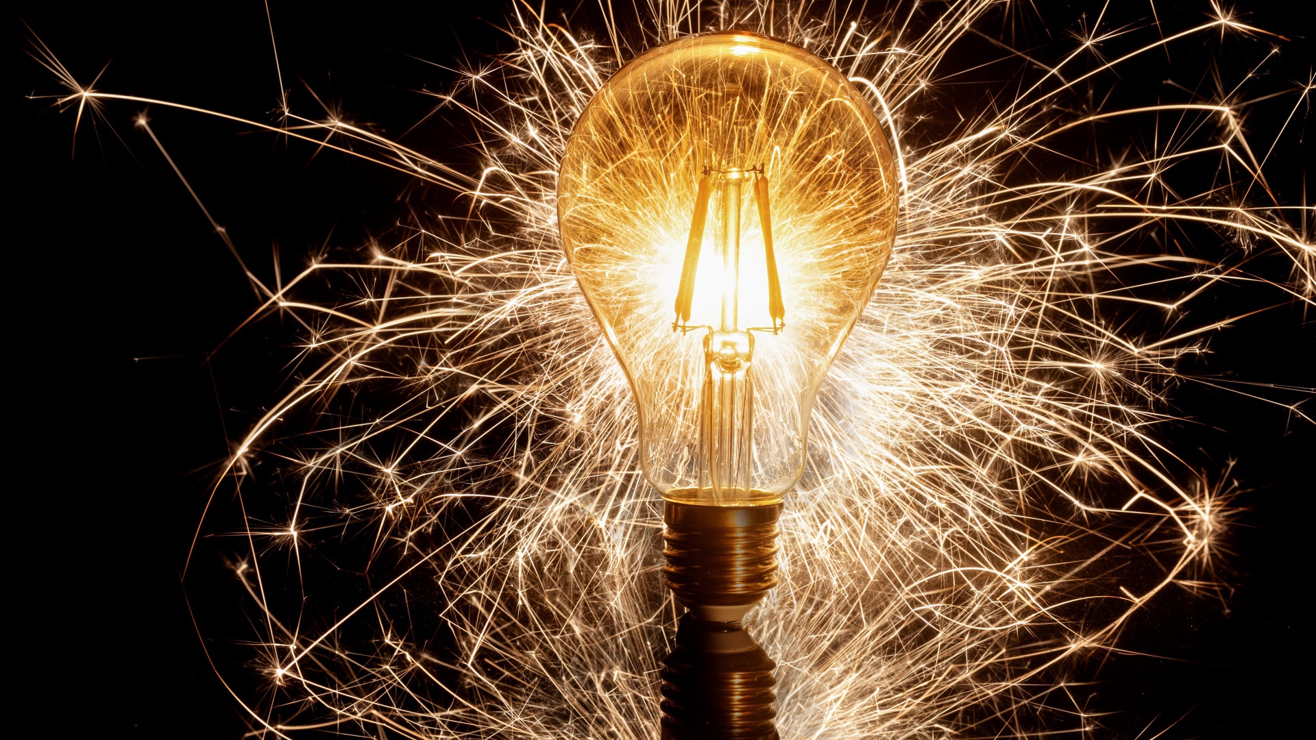 Зажженная лампа на черном фоне с искрами 