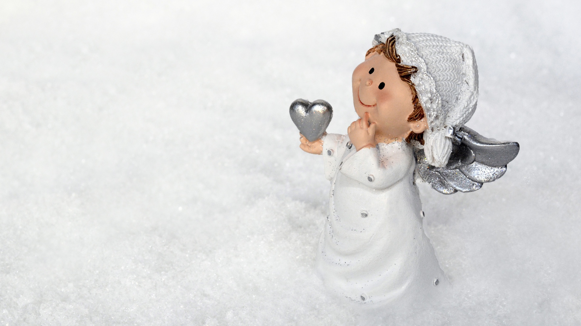 Статуэтка ангела стоит на снегу 