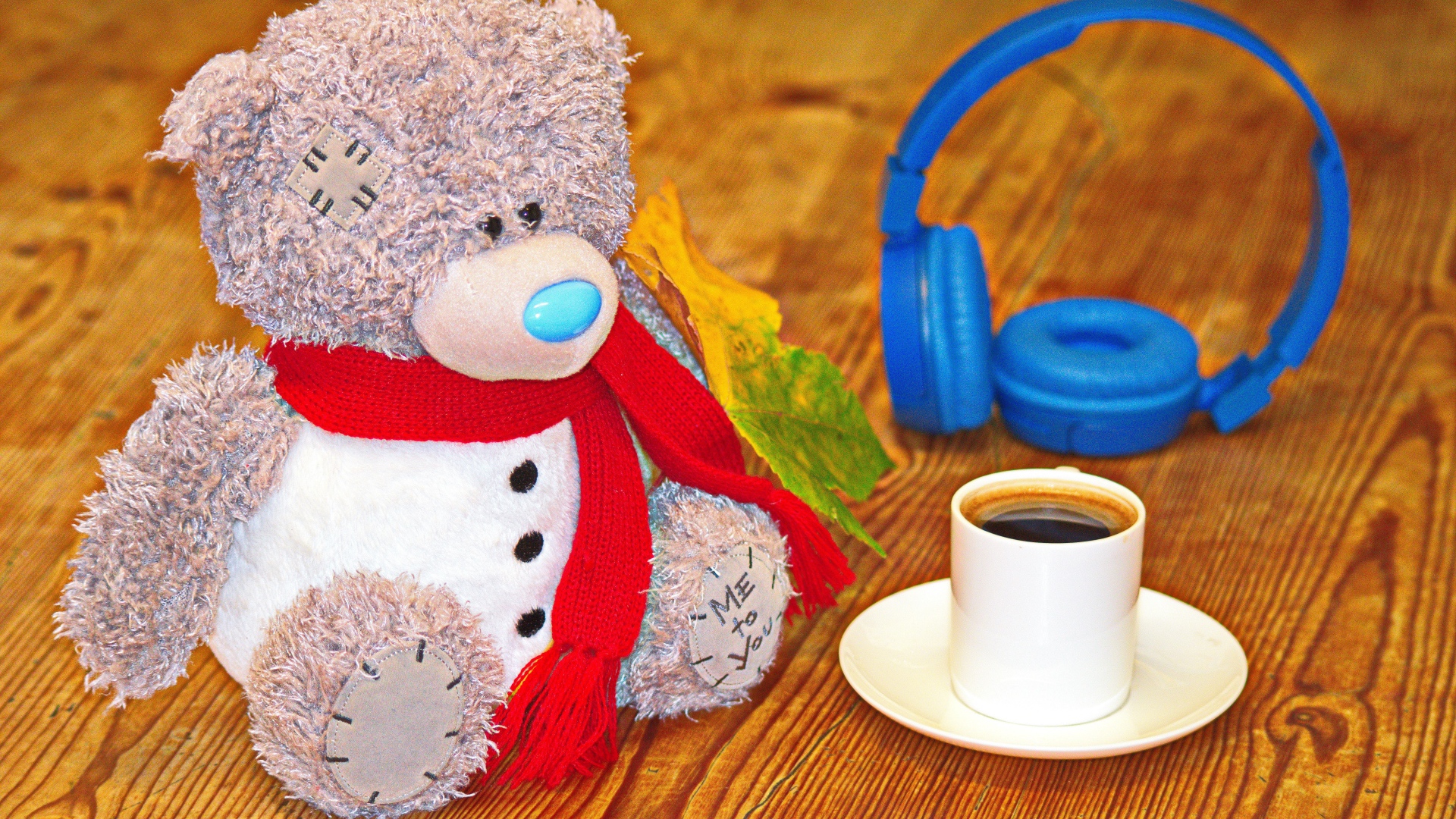 Медведь на столе с чашкой кофе и наушниками 