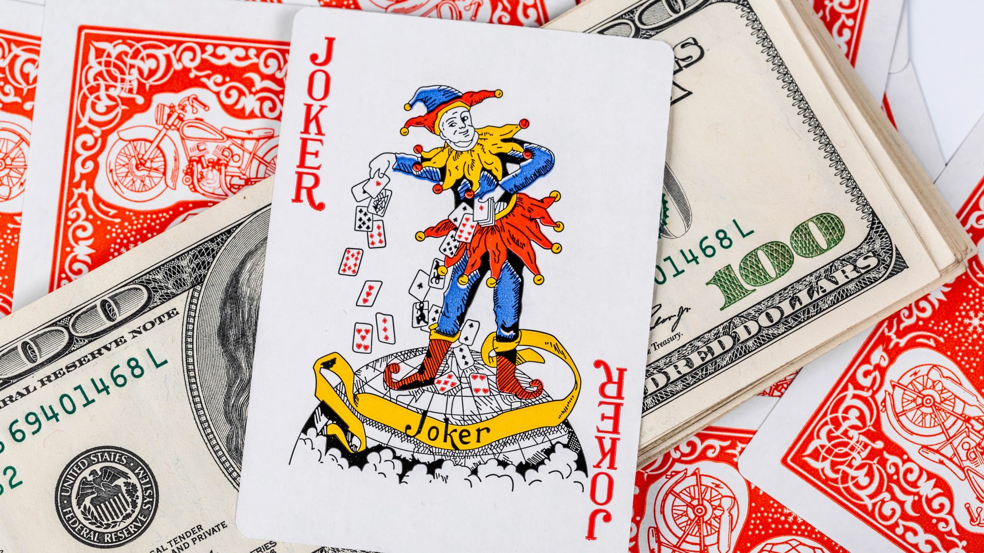 Карточный Джокер и пачка стодолларовых купюр