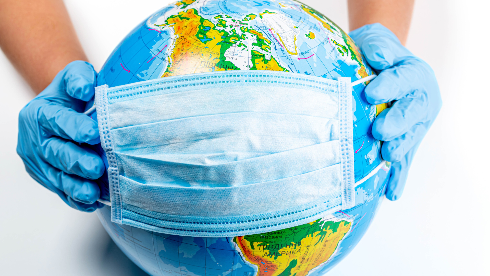 Руки одевают маску от коронавируса на глобус 