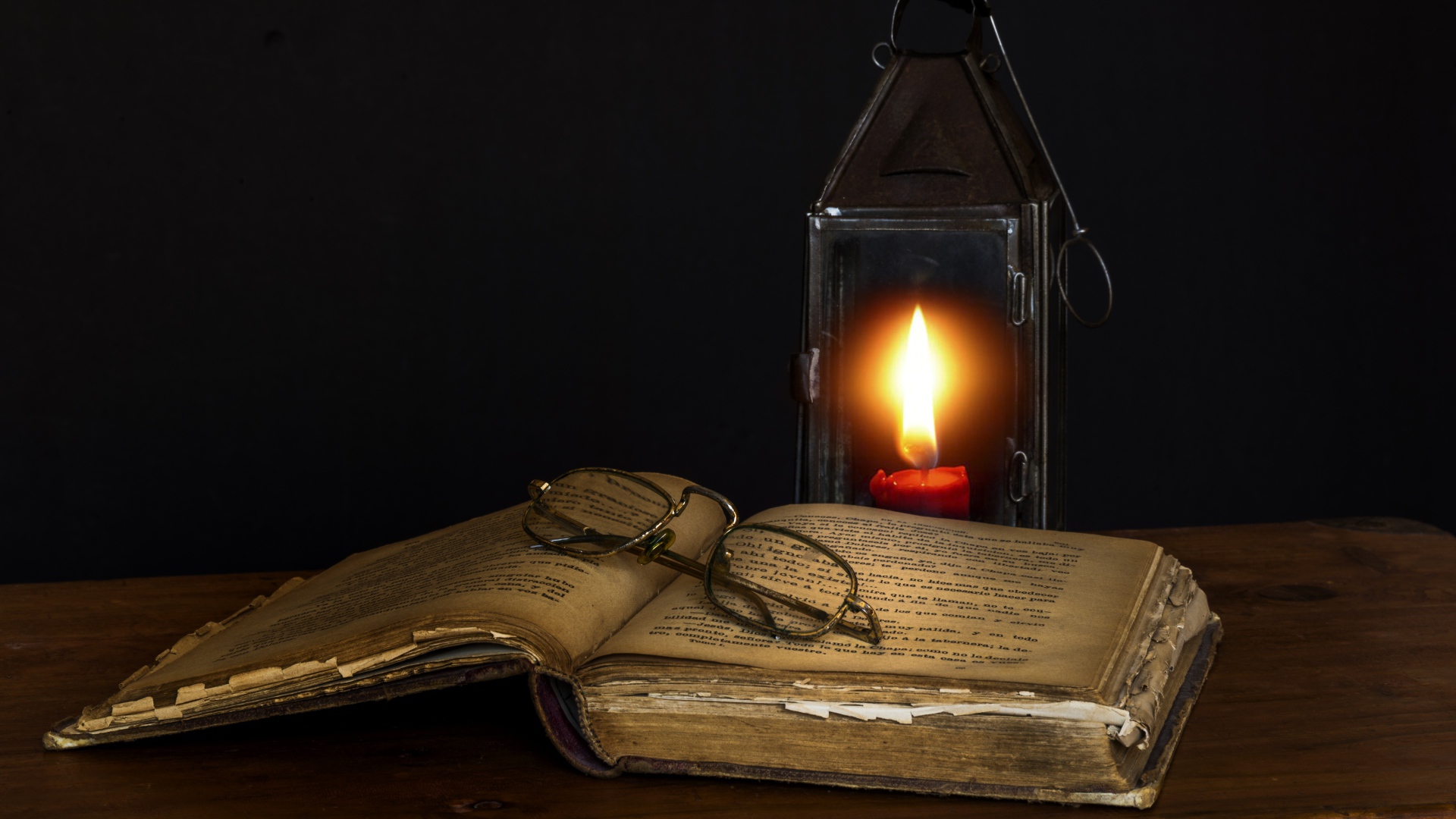 Old book on table with glasses and lamp