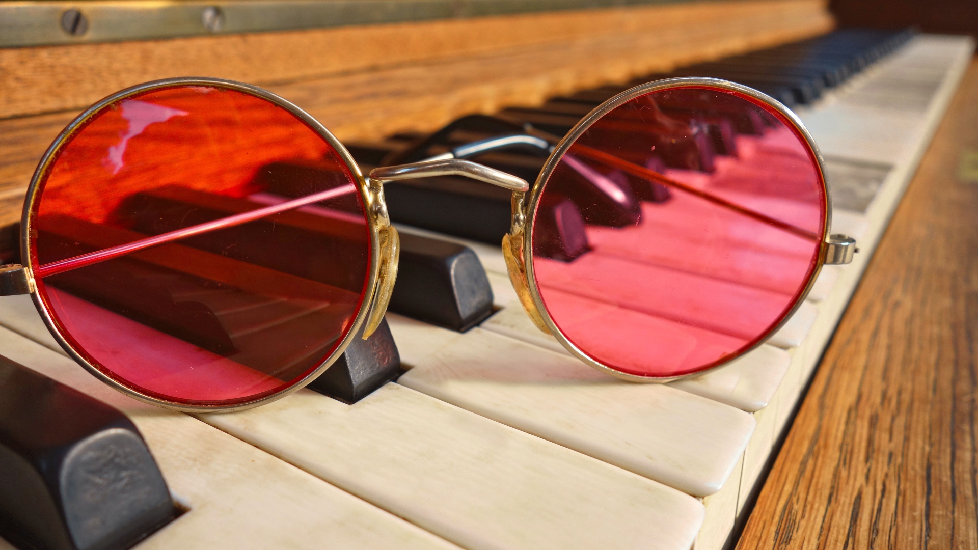 Розовые очки лежат на клавишах рояля