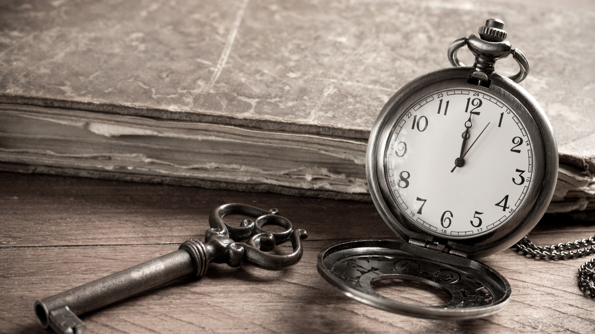 Карманные часы на столе с ключом и старой книгой 