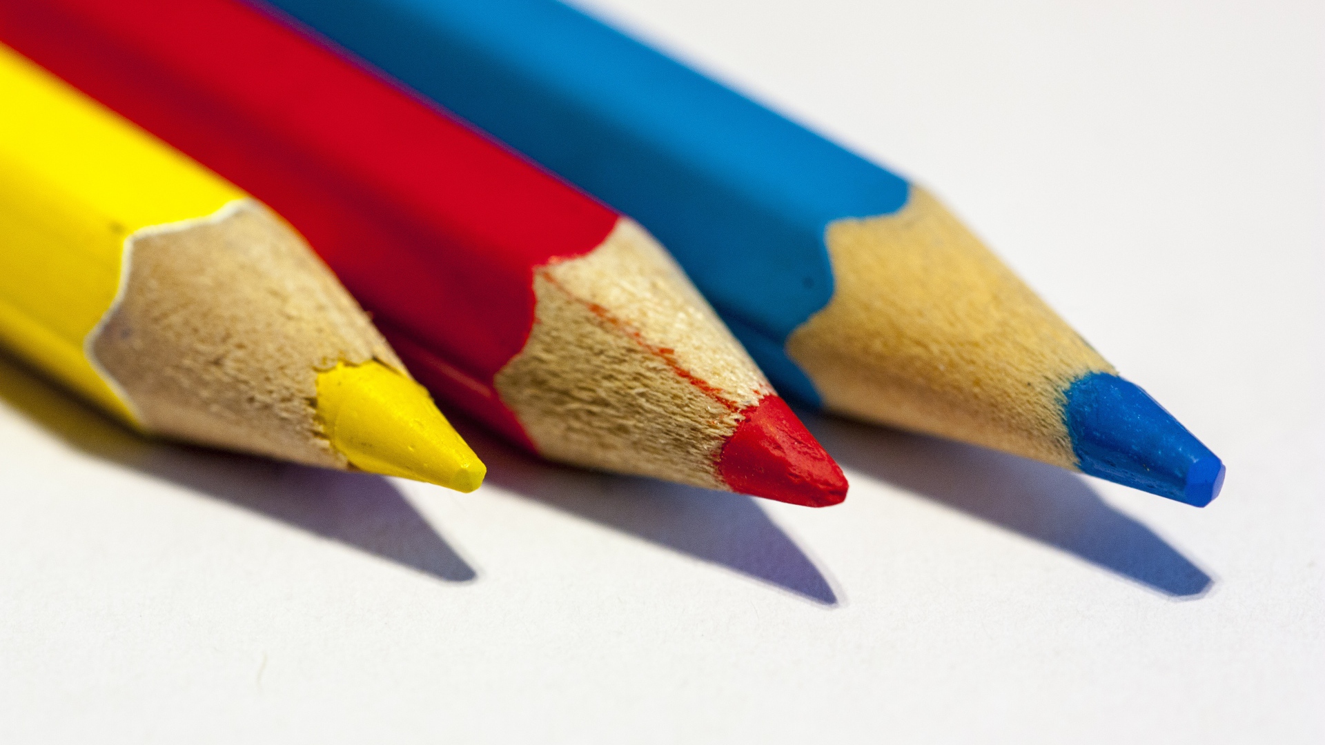 Три разноцветных карандаша на белом фоне